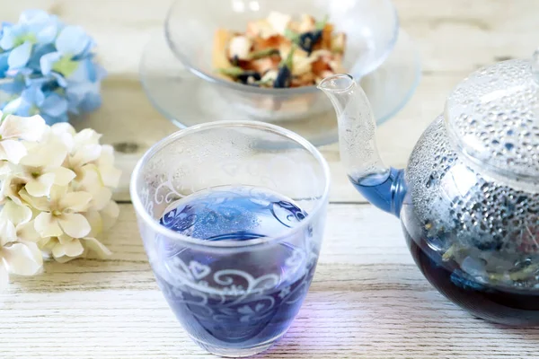 Bright blue color butterfly pea flower herb tea in a glass tea pot and a cup
