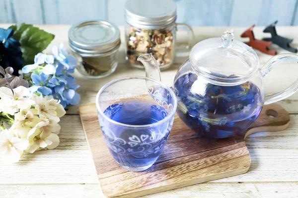 Bright blue color butterfly pea flower herb tea in a glass teapot and a cup