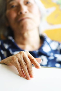 Yaşlı bayanın eli hemşirelik yatağında uzanıyor, yakın plan.