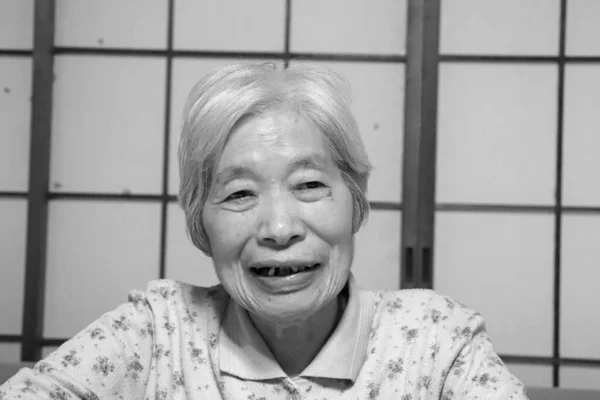Пожилая Женщина Сидящая Перед Экраном Сёдзи Улыбается Смотрит Камеру — стоковое фото