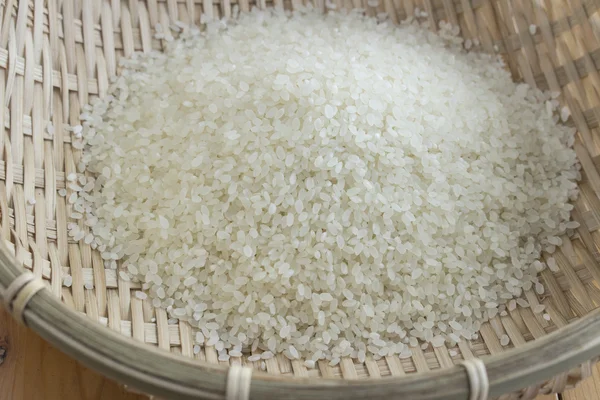 Polished rice in a bamboo basket — Zdjęcie stockowe