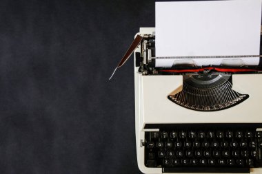 Koyu arkaplanda kağıt olan daktilo. Güzel retro çalışma alanı kapanışı. Bir şeyler yazmak için boş bir yer. Koyu gri arkaplan.