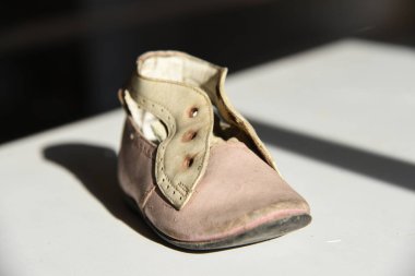 Beyaz arka planda, güneş ışığı ve gölgeli eski püskü ayakkabılar.