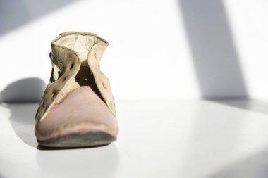 Beyaz arka planda, güneş ışığı ve gölgeli eski püskü ayakkabılar.