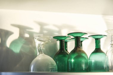 Boş bardaklar baş aşağı, gölgeler ve güneş ışığı raflarda.