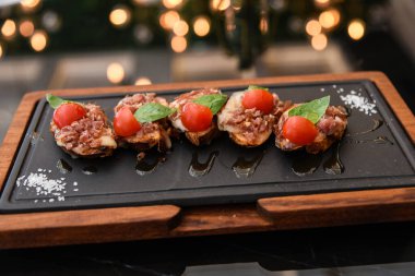 Seramik tahtada zeytinyağı ve fesleğen yapraklı domates bruschetta ekmeği.