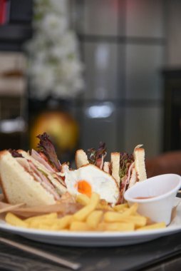 Lezzetli sandviç ve beyaz tabakta kızarmış yumurta..