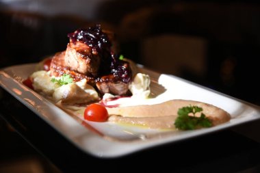 Renkli süslemeli beyaz tabakta büyük bir et huzuru. Elma püresiyle domates ve maydanoz. 