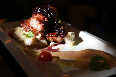 Renkli süslemeli beyaz tabakta büyük bir et huzuru. Elma püresiyle domates ve maydanoz. 