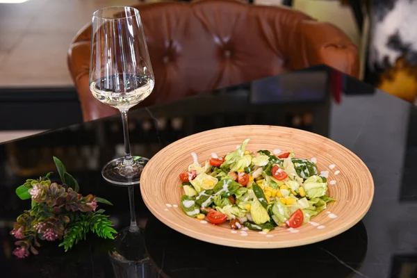 Seramik tabakta taze salata ve bir bardak şarap.