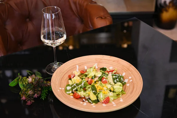 Seramik tabakta taze salata ve bir bardak şarap.