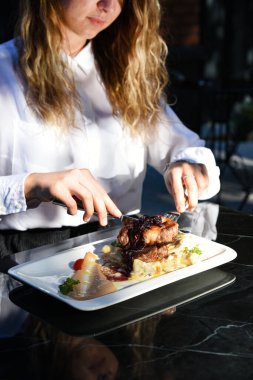 Kadın eli işte. Dekoratif yemek yiyen bir kız. Dekorasyonlu ızgara et. Güneş ışığı ve gölgeler