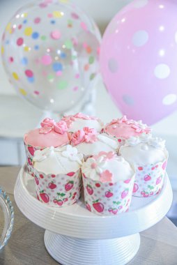 Kremalı ve şekerli güzel bir pasta ve arka planda balonlar. Dekoratif bardaklarda çörekler. Kurdeleli geleneksel pasta.. 