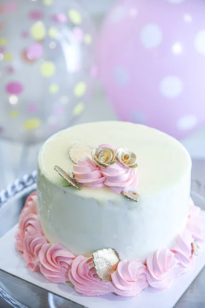 Beautiful cake with icing and sugar decoration with balloons in background. Muffins in decorative cups. Traditional cake with icing ribbon.