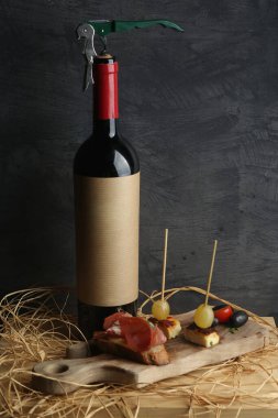 Şarap şişesi ve kanepe tahtanın üzerinde gri tarafsız arka plan ve masa dekorasyonu..