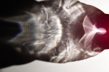 Camın içinden ışık geçiyor. Beyaz arkaplanda soyut renkli gölgeler. 