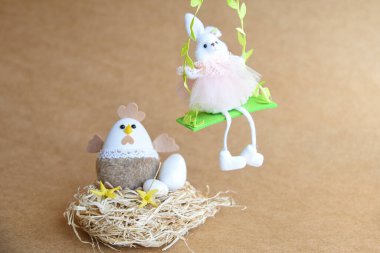 Güzel bir Paskalya süsü. Tavşanlar, tavuklar, yumurtalar, yuvalar, havuçlar, çiçekler ve ruh. Çiçekli salıncakta tavşan, anne tavuk ve yumurta. 