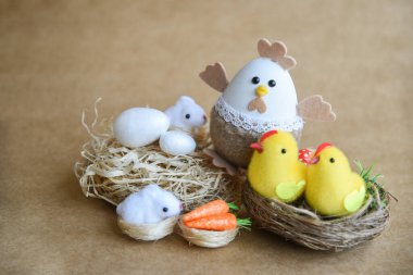 Güzel bir Paskalya süsü. Tavşanlar, tavuklar, yumurtalar, yuvalar, havuçlar, çiçekler ve ruh. Çiçekli salıncakta tavşan, anne tavuk ve yumurta. 