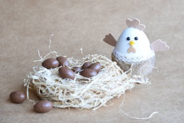 Yuvadaki Paskalya yumurtaları. Çikolata yumurtaları, tavşanlar, çiçekler ve doğal arka plan süslemeleri. Boş kopya alanı olan Paskalya arkaplanı