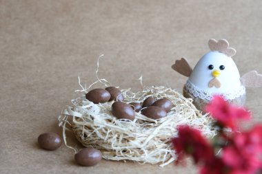 Yuvadaki Paskalya yumurtaları. Çikolata yumurtaları, tavşanlar, çiçekler ve doğal arka plan süslemeleri. Boş kopya alanı olan Paskalya arkaplanı