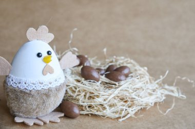 Yuvadaki Paskalya yumurtaları. Çikolata yumurtaları, tavşanlar, çiçekler ve doğal arka plan süslemeleri. Boş kopya alanı olan Paskalya arkaplanı