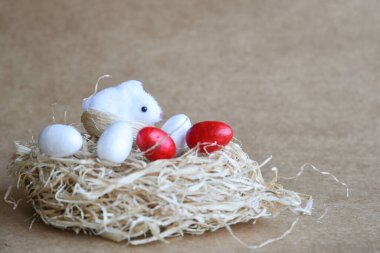 Yuvadaki Paskalya yumurtaları. Çikolata yumurtaları, tavşanlar, çiçekler ve doğal arka plan süslemeleri. Boş kopya alanı olan Paskalya arkaplanı