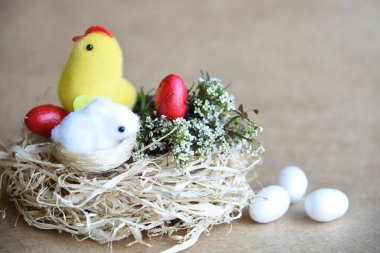 Yuvadaki Paskalya yumurtaları. Çikolata yumurtaları, tavşanlar, çiçekler ve doğal arka plan süslemeleri. Boş kopya alanı olan Paskalya arkaplanı