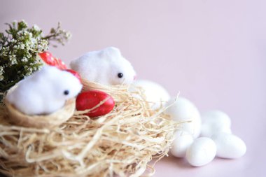 Yuvasında güzel yavru tavşanlar ve açık pembe arka planda Paskalya yumurtaları. Boş kopya alanı olan Paskalya kartpostalı