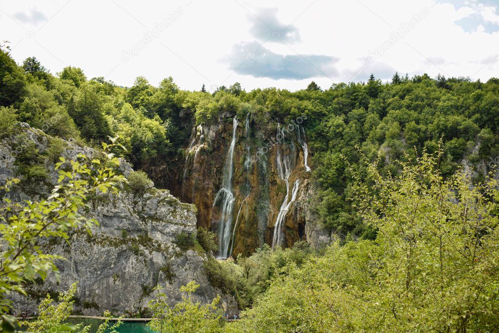 Beautiful landscape with lot of vegetation and water. Blue lake water, water falls, mountains and grass.