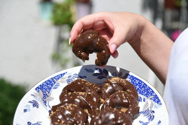 Hand holding chocolate croissant with dripping chocolate. Delicious desert from bakery. Croissants arranged on plate. commercial