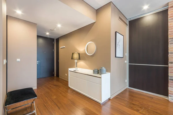 Entrance hall in the bright modern apartment. Hallway dresser with lamp