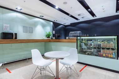 Minimalist bir matarada iki kişilik bir masa. Ahşap tezgah ve mikrodalga fırın.