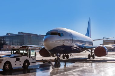 Bir yolcu uçağı hangarda römorkör Pushback traktör taşır.