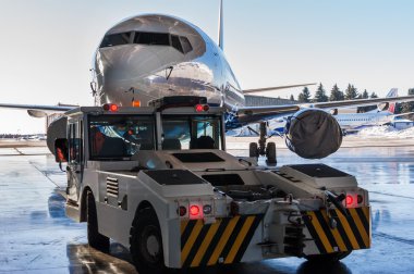 Römorkör Pushback traktör bir yolcu uçağı hangardan taşır.