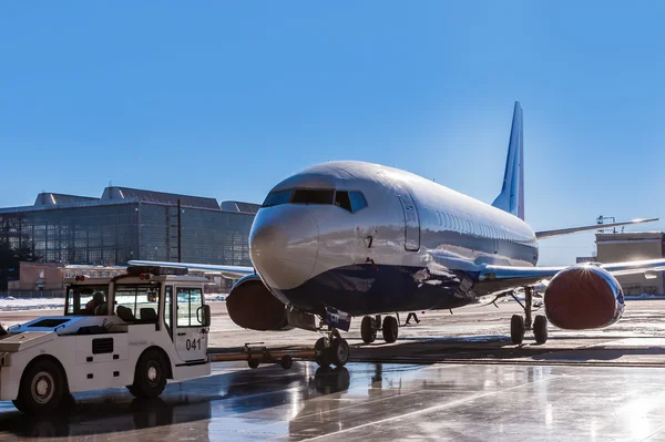 Bir yolcu uçağı hangarda römorkör Pushback traktör taşır.