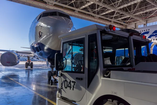 Römorkör Pushback traktör bir yolcu uçağı hangardan taşır.