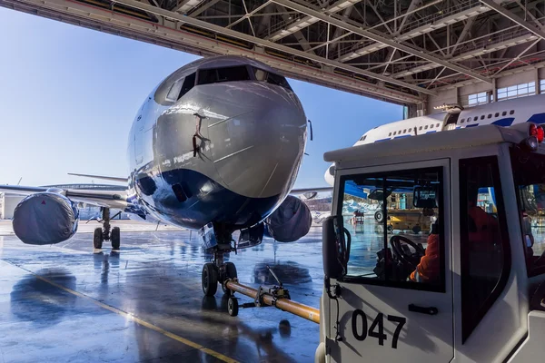 Vytlačení vlečný remorkér nese cestující jet v hangáru. — Stock fotografie