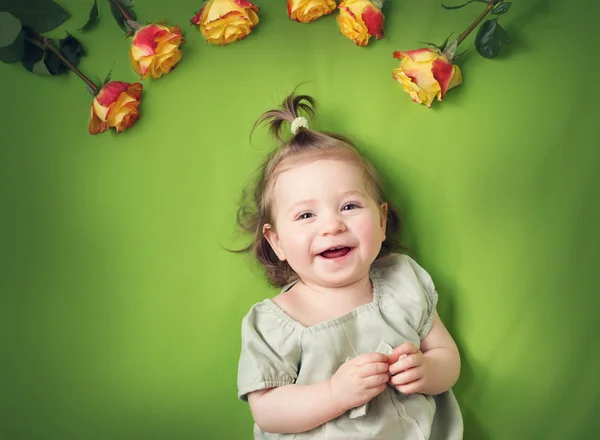 Menina bonita deitada no cobertor verde com rosas amarelas — Fotografia de Stock