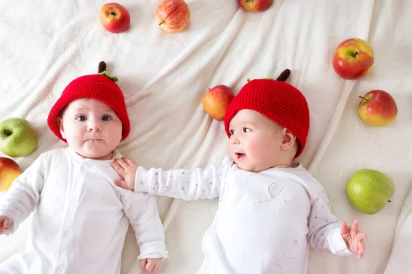 Dois bebês bonitos deitado em chapéus em cobertor macio com maçãs — Fotografia de Stock