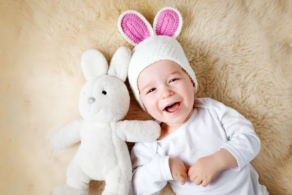 Ett år gammal baby liggande i kanin hatt på lamm ull — Stockfoto