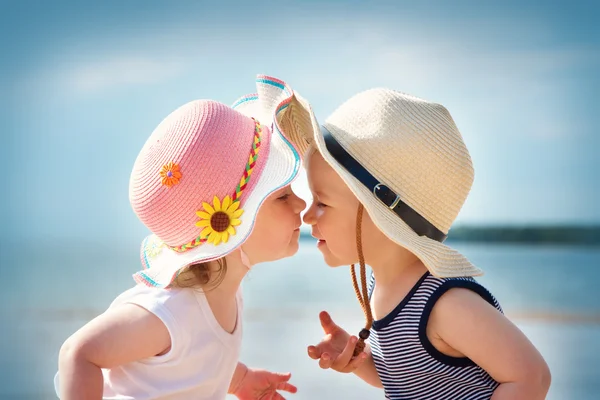 Babygirl and babyboy kiss on the beach — стоковое фото
