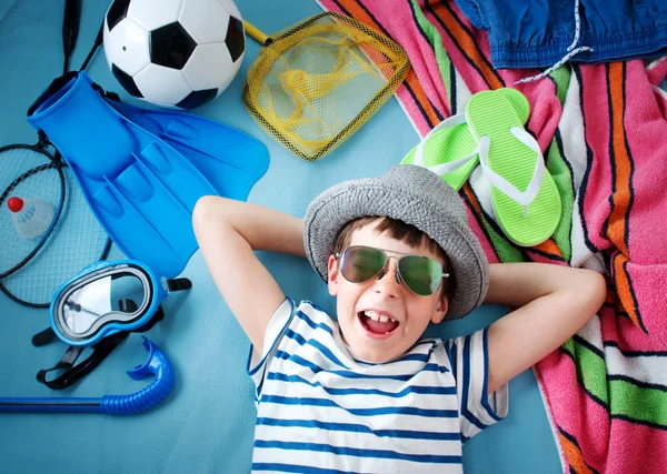 Хлопчик з сонцезахисними окулярами та іграшками на синьому фоні — стокове фото