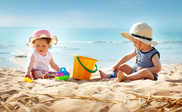 Babygirl i babyboy siedzi na plaży — Zdjęcie stockowe