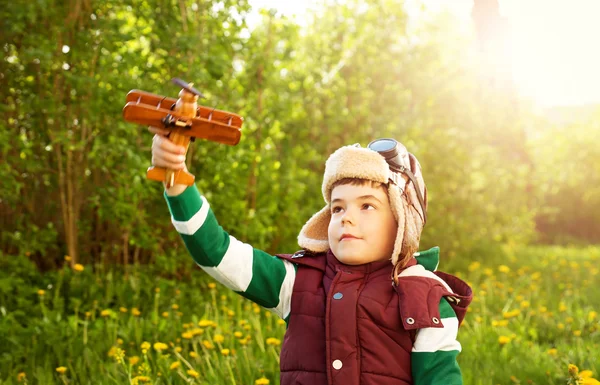 Boy playing in aviator hat with old plane — Stock Photo, Image