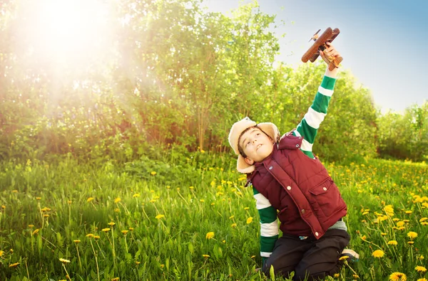 Boy playing in aviator hat with old plane — Stock Photo, Image