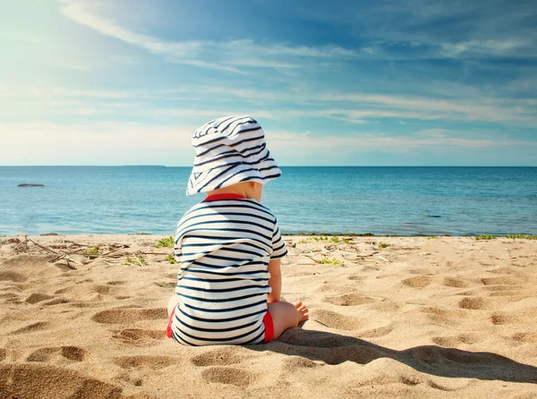 Malý chlapeček sedí na pláži v letní den — Stock fotografie