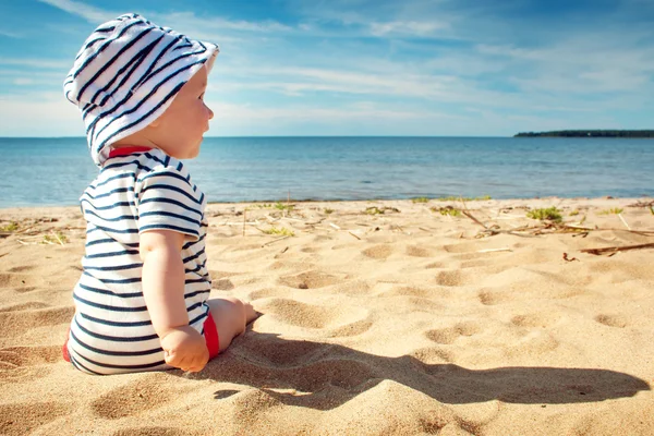 Pequeño niño sentado en la playa en el día de verano — Foto de Stock