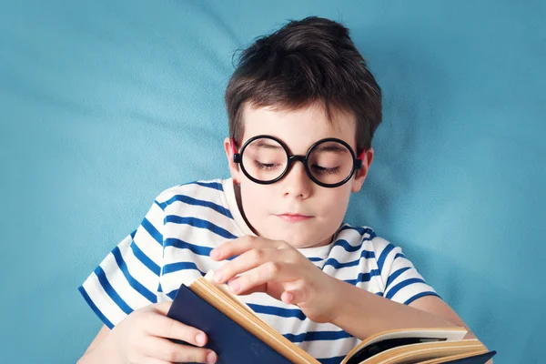 Niño de siete años acostado con libro — Foto de Stock