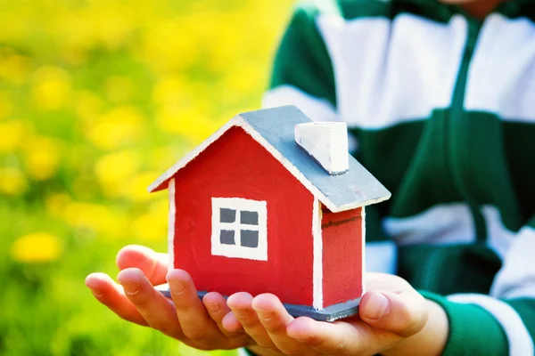 Manos de niños sosteniendo casa modelo rojo — Foto de Stock