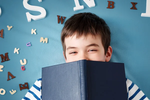 Niño de siete años acostado con libro y cartas — Foto de Stock